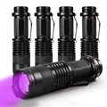 Set of black flashlights with one emitting purple light on a white background